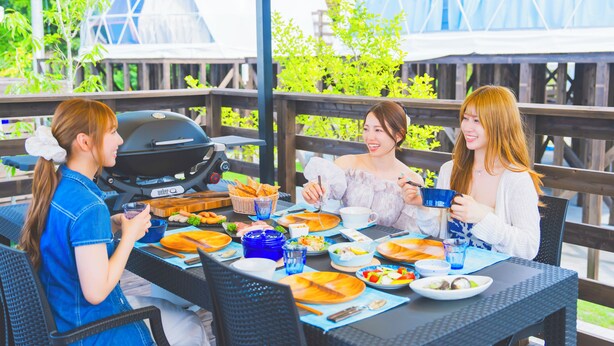 An outdoor dining area with a grill, tables, chairs, and a view of greenery. - GLAMPREMIER Naruto (Naruto-shi Naruto-cho)