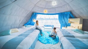 A tent-style room with two beds, a central seating area, and a view through a large window. - GLAMPREMIER Naruto (Naruto-shi Naruto-cho)