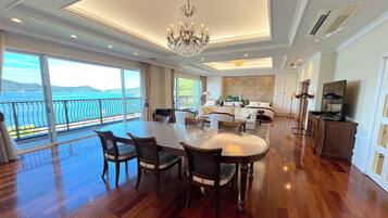 A spacious living area with a dining table, seating, and a view of the sea.