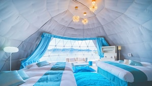 A tent-style room with a bed, a sofa, and a table.
