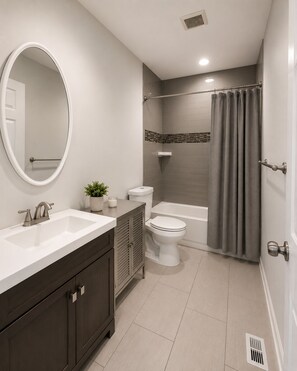 A modern bathroom with a vanity, sink, mirror, toilet, bathtub, shower curtain, and a potted plant. - A modern artsy 3 bedroom/3.5 bathroom townhome in Baltimore AKA Charm City (Baltimore)