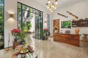 Un hall d’entrée spacieux avec un comptoir de réception, de grandes fenêtres et des plantes d’intérieur.