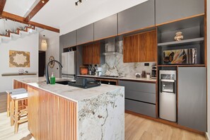 A modern kitchen with a marble island, wooden cabinets, and a built-in water dispenser. - 4BR/4.5 Bath Serviced Villa - Private Pool + Jacuzzi + Staff - BLUE DEER TULUM (Tulum)