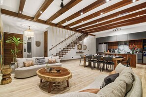 A spacious living room with a wooden ceiling, a staircase, a dining area, and a kitchen. - 4BR/4.5 Bath Serviced Villa - Private Pool + Jacuzzi + Staff - BLUE DEER TULUM (Tulum)