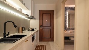 A modern kitchen with a built-in stove, a coffee maker, and a sink. - Maison De Gu Thi Sách Apartment (Ben Nghe)