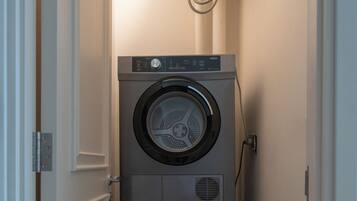 A laundry room with two stacked front-loading washing machines and a water heater above.