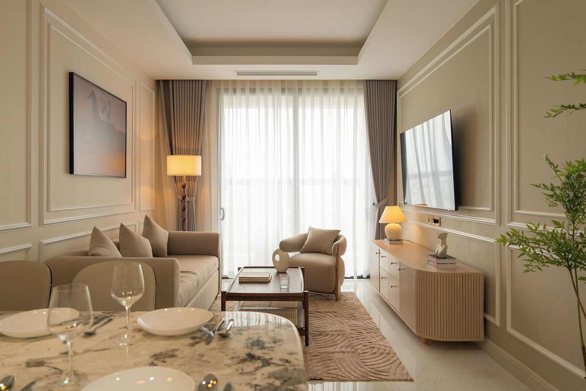 A modern living room with a sofa, armchair, coffee table, and a dining area with a marble table and chairs.