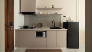 Eine moderne Küche mit Einbauofen, einem schwarzen Kühlschrank und einem Edelstahl-Wasserkocher.