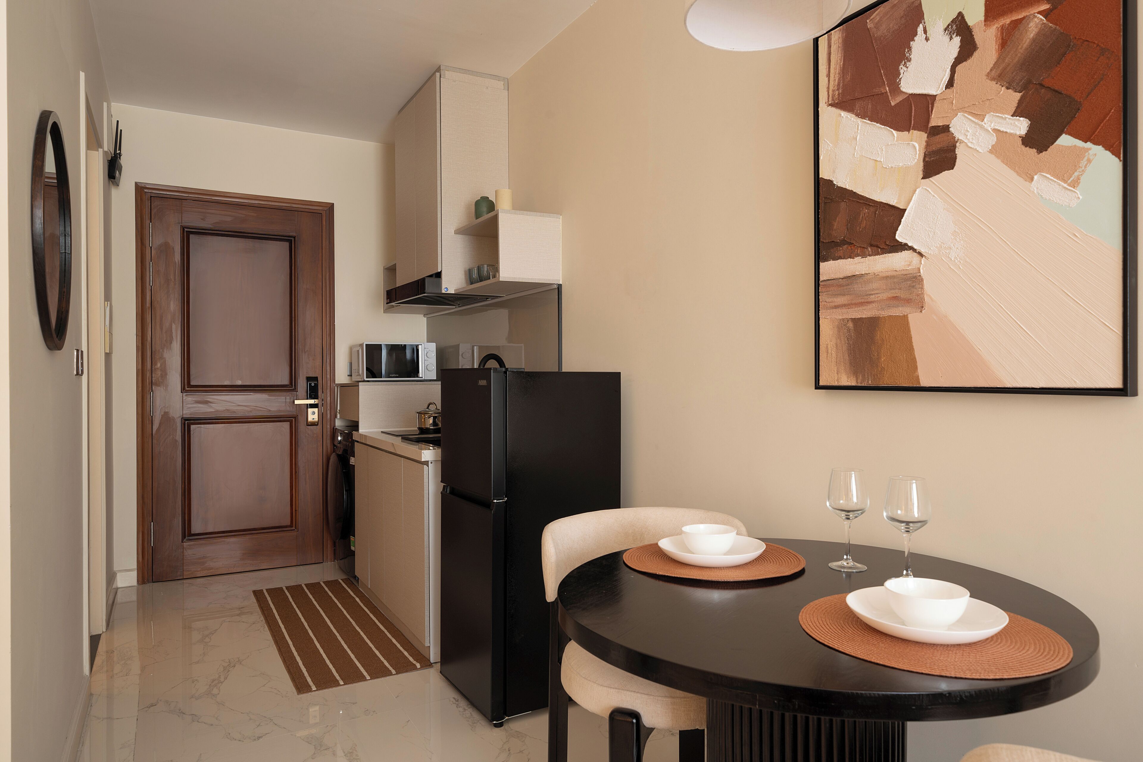 A compact kitchen with a refrigerator, microwave, and a dining area with a table and chairs.
