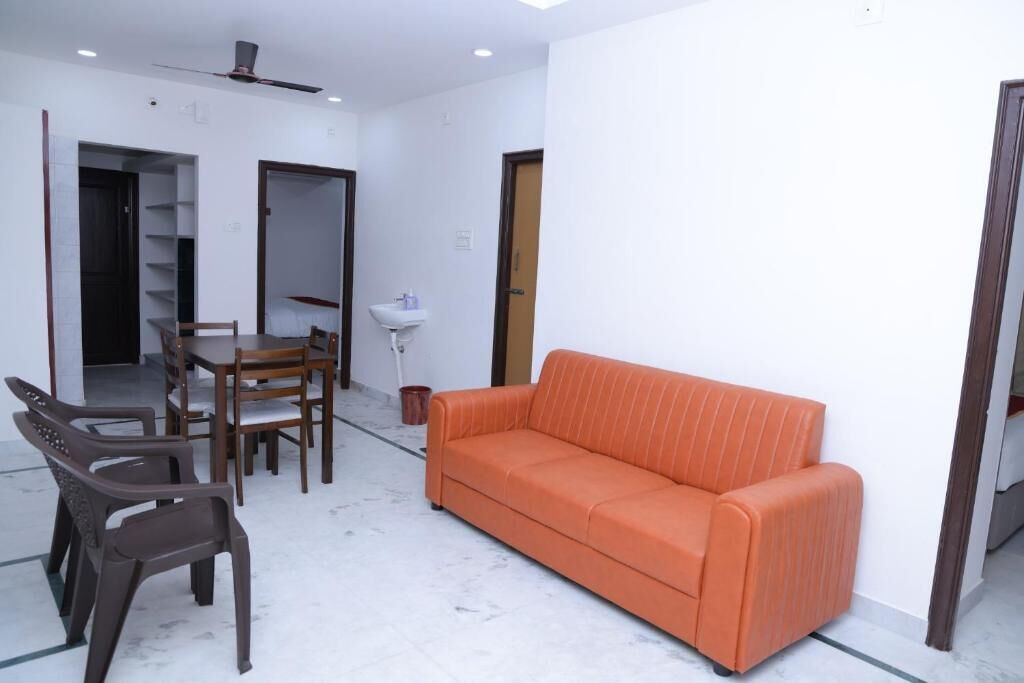 Una habitación con sofá, mesa de comedor, sillas y un lavamanos.