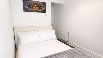 Een slaapkamer met een bed, een radiator en een schilderij aan de muur.