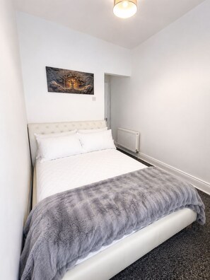 A bedroom with a bed, a radiator, and a painting on the wall. - Modern, stylish and comfortable 2-Bed Home, Minutes from Newcastle City Centre (Gateshead)