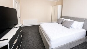 Ein Hotelzimmer mit Bett, Fernseher, Heizkörper und Kleiderschrank.