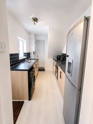 Una cocina moderna con lavadora integrada, refrigerador y cafetera.
