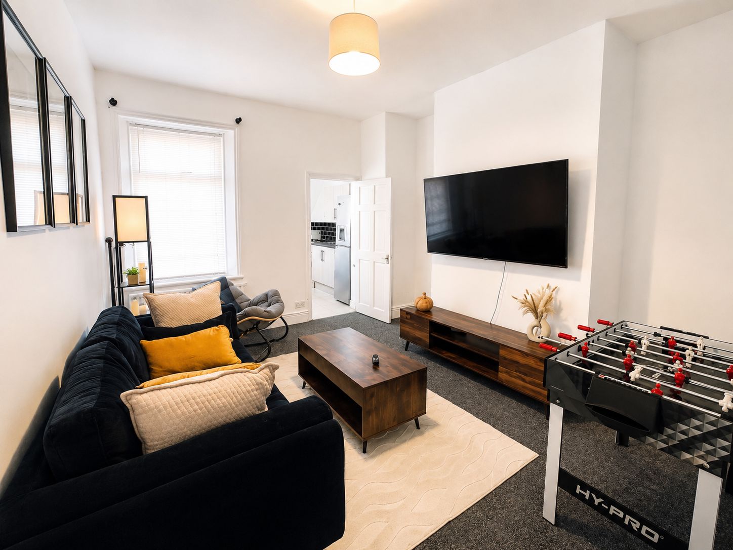 Een moderne woonkamer met een bank, salontafel en een tafelvoetbaltafel.