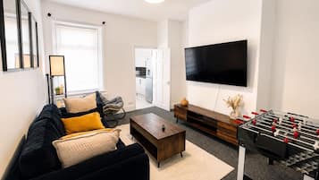Een moderne woonkamer met een bank, salontafel en een tafelvoetbaltafel.