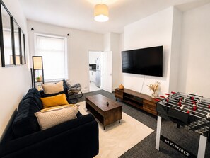 A modern living room with a sofa, coffee table, and a foosball table. - Modern, stylish and comfortable 2-Bed Home, Minutes from Newcastle City Centre (Gateshead)