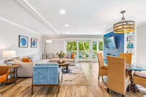 Uma sala de estar moderna com um sofá, cadeiras, uma mesa de centro e uma TV fixada na parede.