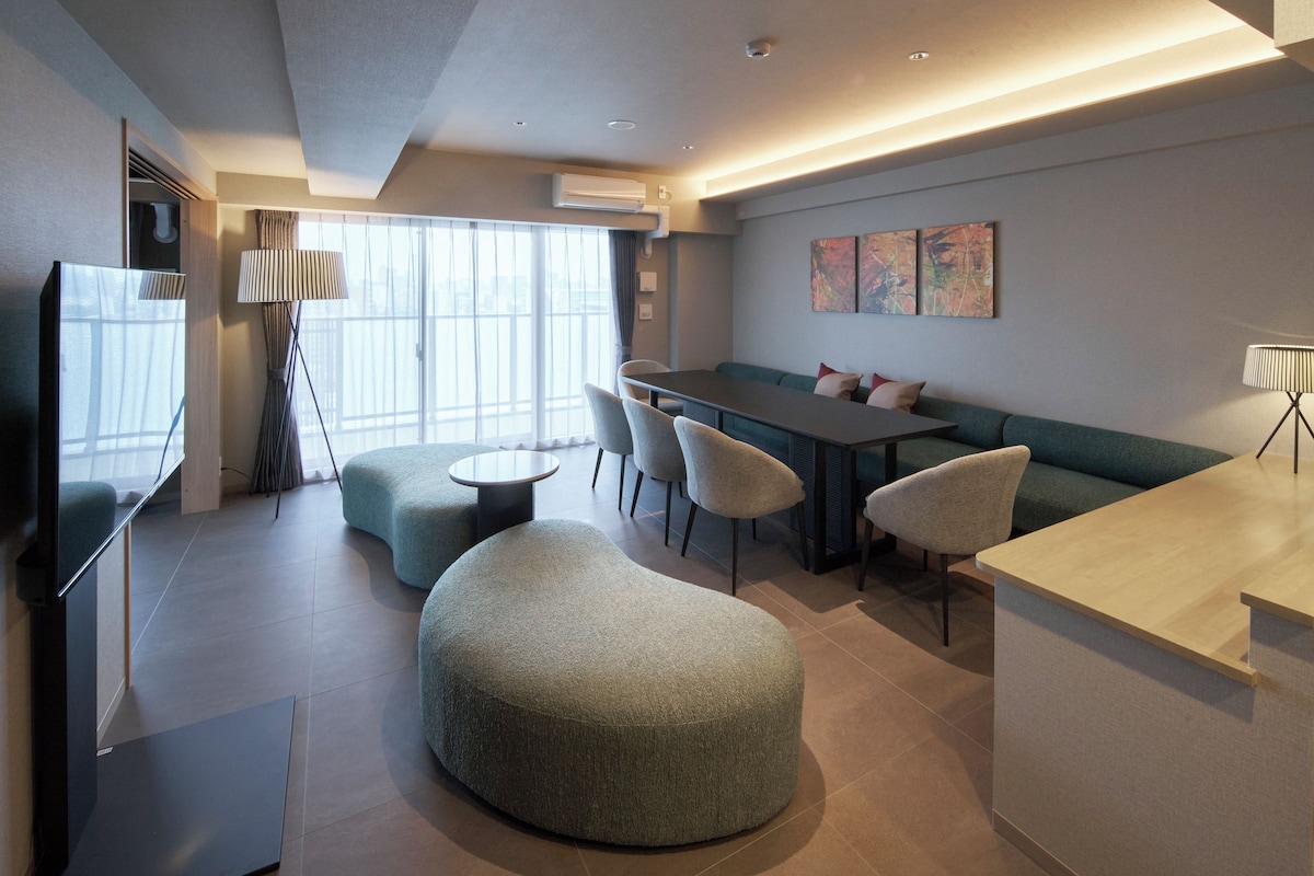 A modern living room with a sofa, ottoman, and dining area.