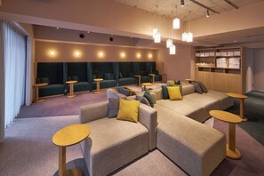 A modern lounge area with sofas and round tables, a wooden cabinet with towels, and pendant lighting. - KOUSA Osaka Namba (Osaka)