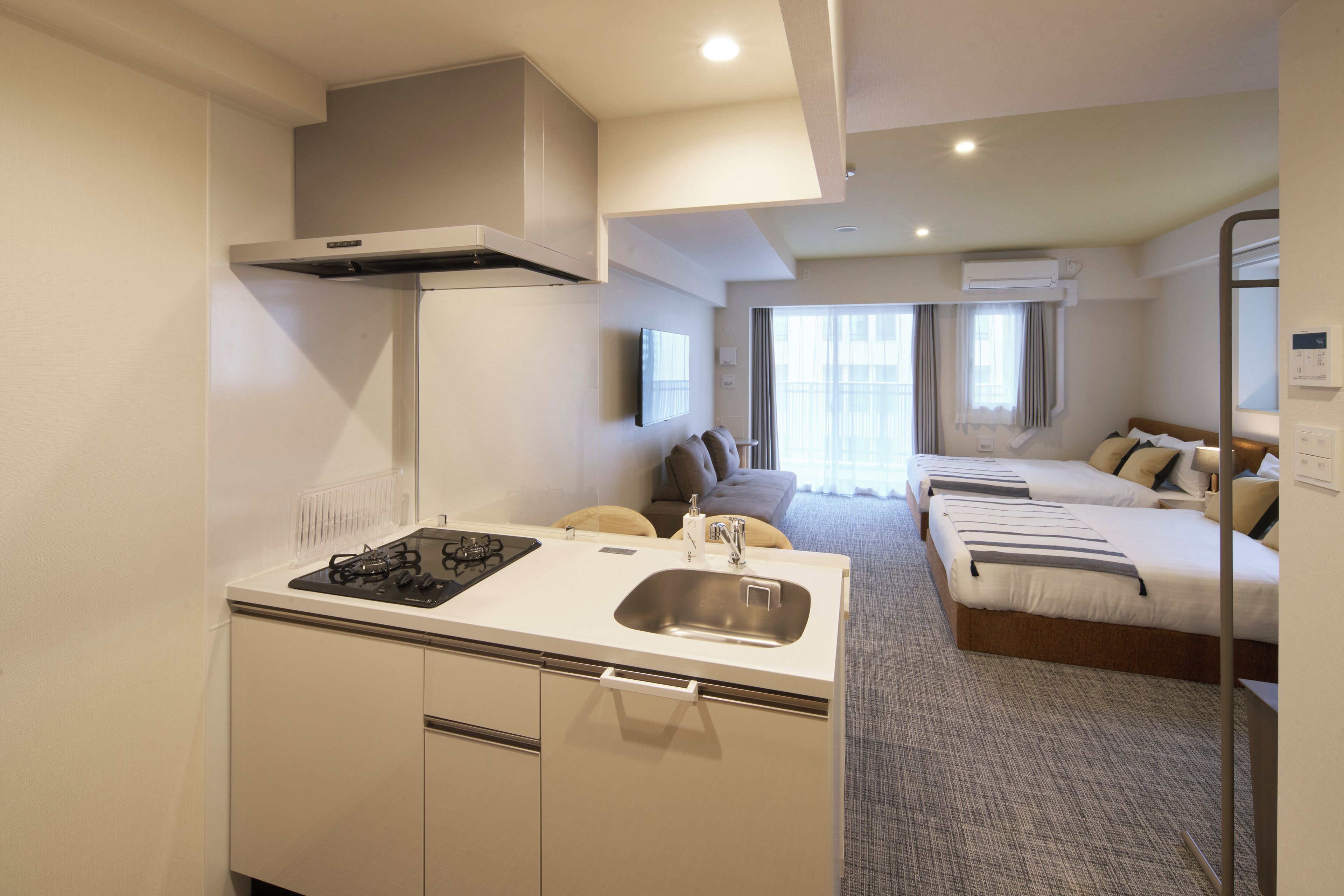 A compact hotel room with a kitchenette, a bed, and a bathroom.