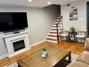 A living room with a fireplace, a television, a staircase, and a coffee table with a plant. - Luxury Lincolnwood 3BR 2BA furnished midterm. Utilities and wifi included. (Lincolnwood)