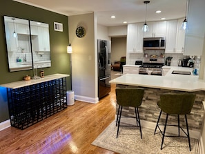 A modern kitchen with white cabinets, a stainless steel refrigerator, and a large island with bar stools. - Luxury Lincolnwood 3BR 2BA furnished midterm. Utilities and wifi included. (Lincolnwood)