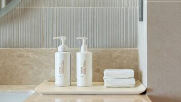 A bathroom counter with two bottles of body lotion and a stack of white towels.