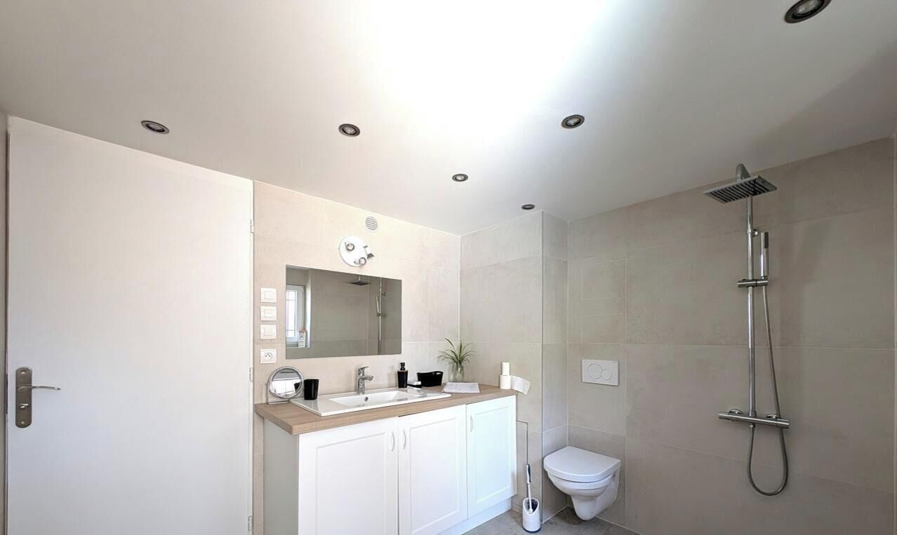 Une salle de bain moderne équipée d’une douche, de toilettes et d’un meuble-lavabo.