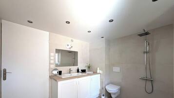 Une salle de bain moderne équipée d’une douche, de toilettes et d’un meuble-lavabo.
