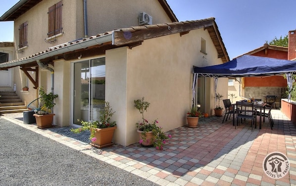 Una casa con un porche techado, mobiliario exterior y plantas en macetas.