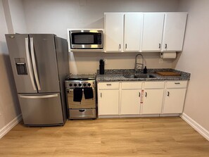 A compact kitchen with a refrigerator, microwave, stove, and white cabinets. - Modern 1BR Tampa Stay Near Downtown (Tampa)