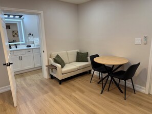 A compact living space with a kitchenette, a sofa, a round table, and two chairs. - Modern 1BR Tampa Stay Near Downtown (Tampa)