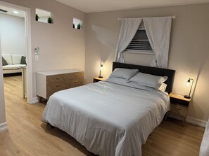A bedroom with a bed, bedside tables, a nightstand, a dresser, a mirror, and a window with curtains. - Modern 1BR Tampa Stay Near Downtown (Tampa)