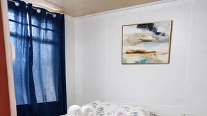 Une chambre à coucher avec un lit, une petite table de chevet, une lampe et un tableau au mur.