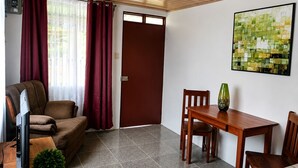 Un salon avec un canapé, un téléviseur et une table à manger avec des chaises.