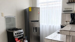 Une cuisine équipée d’une cuisinière à gaz, d’un réfrigérateur en acier inoxydable et d’un dosseret carrelé.
