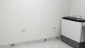 Un lavadero con lavadora, paredes blancas y baldosas de piso con diseño de mármol.