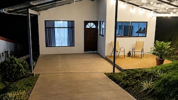 Una casa moderna con un porche cubierto, entrada de concreto y un pequeño jardín.