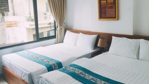 Habitació d'hotel amb dos llits, una finestra gran, una cortina i un quadre encimbellat a la paret.