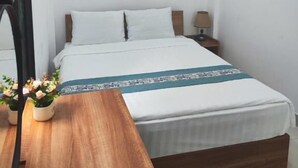Un dormitorio con cama, mesita de noche, lámpara y dos cuadros en la pared.