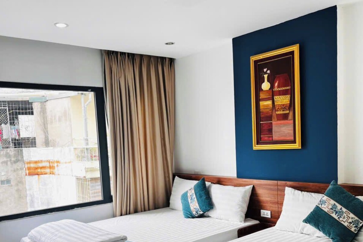 A hotel room with two beds, a large window, and a framed picture on the wall.