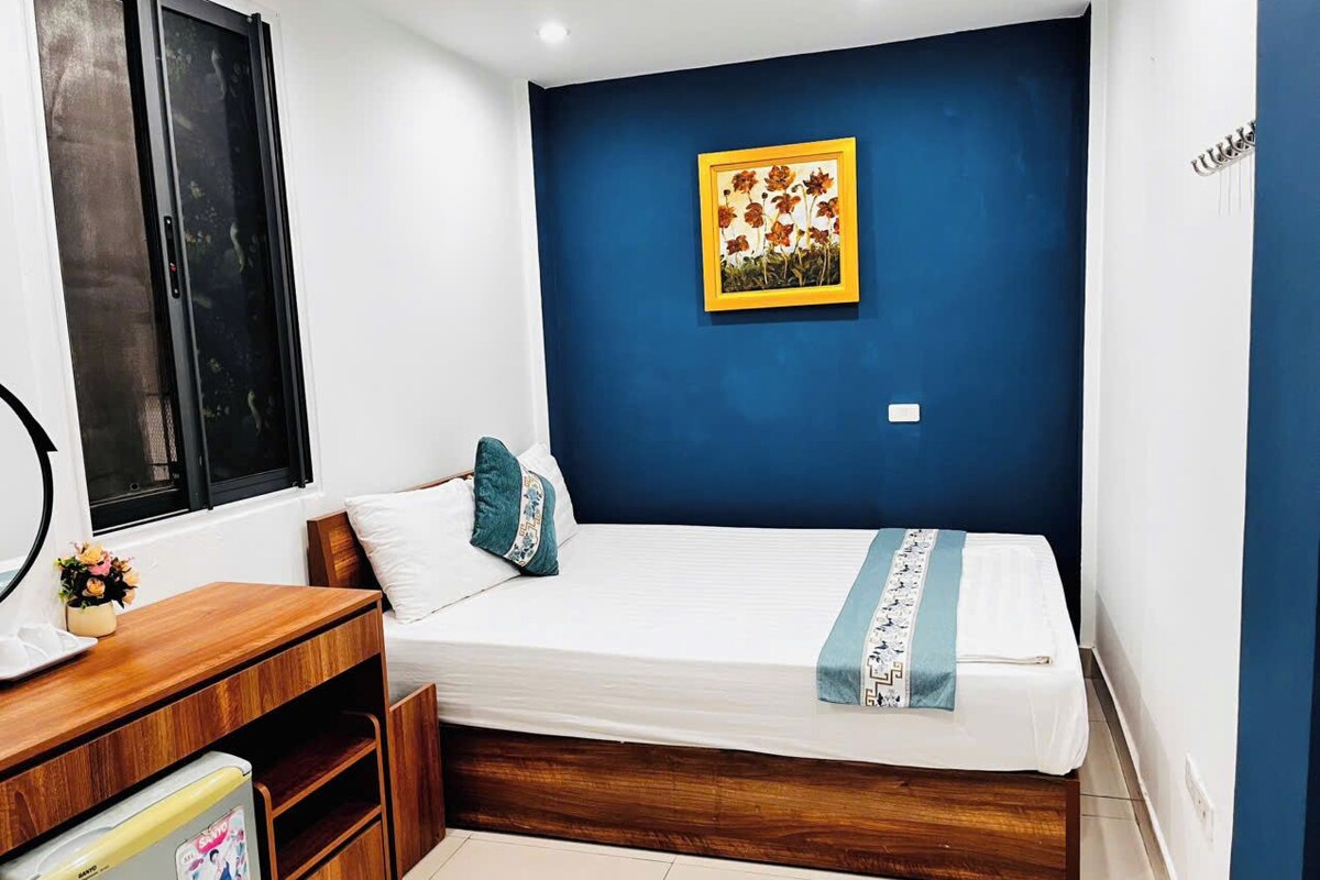 A bedroom with a bed, a desk, and a window.