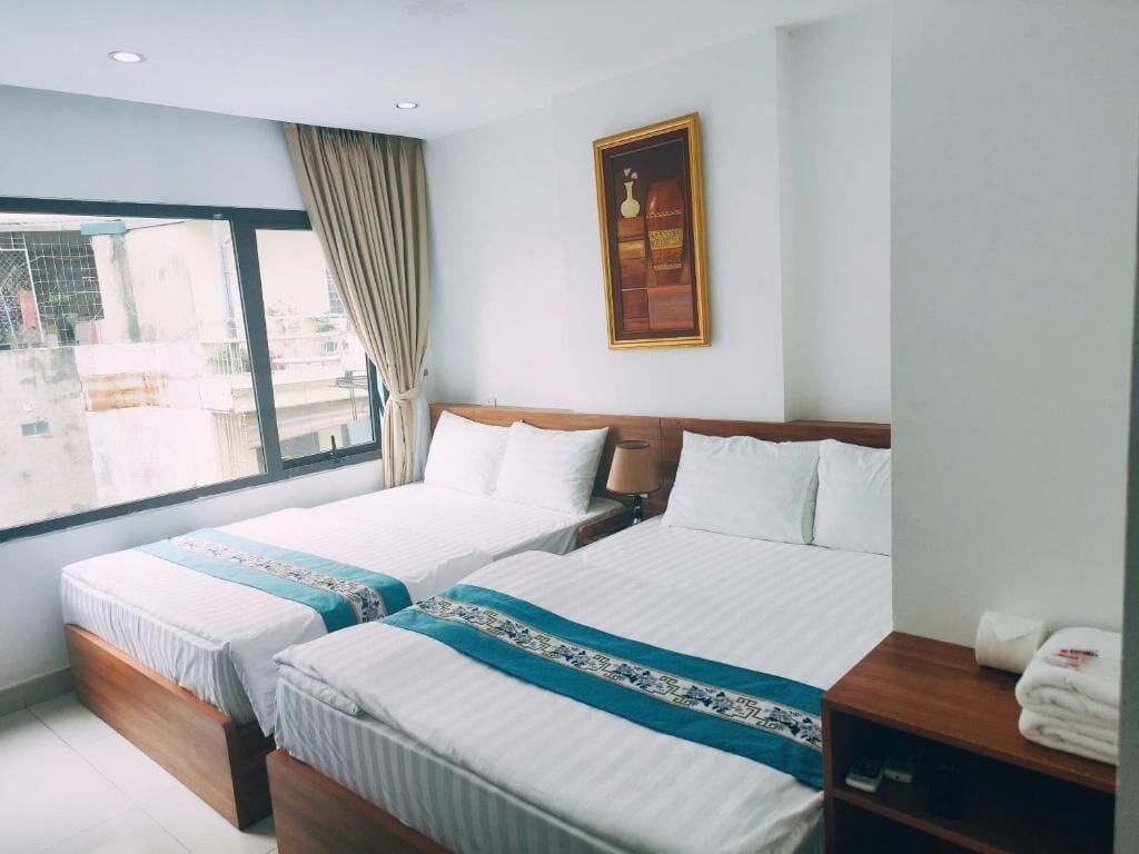Una habitación de hotel con dos camas, un ventanal grande y un cuadro en la pared.