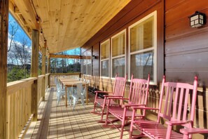 A wooden deck with a railing, a table, and several chairs. - Private Indoor Pool, Hot Tub, Game Room, Sleeps 12 · 20 Min to Pigeon Forge (Sevierville)