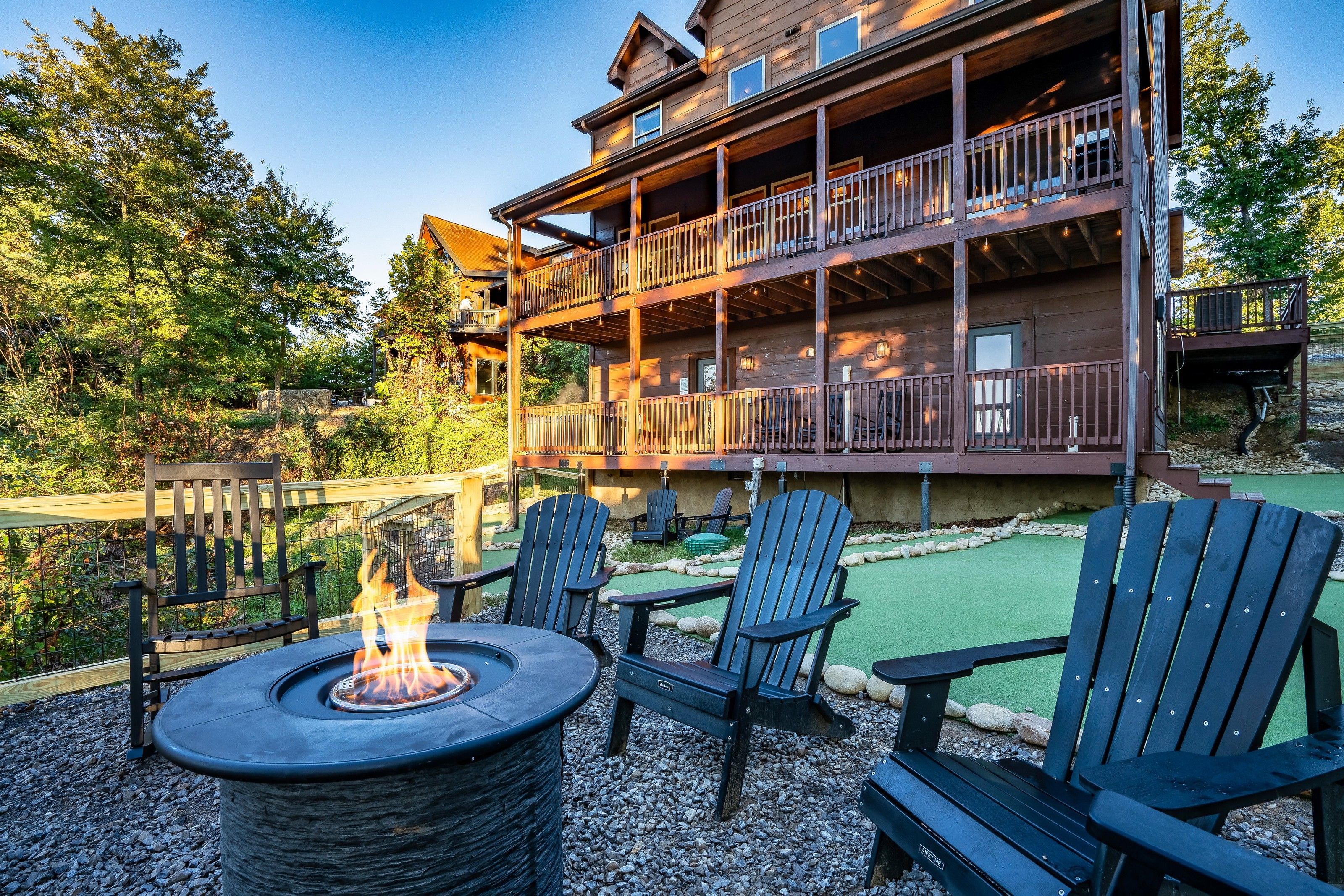A lodge with a fire pit and Adirondack chairs in the outdoor seating area.