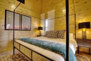 A wooden-paneled bedroom with a bed, two bedside tables, a floor lamp, and two wall-mounted lamps. - Private Indoor Pool, Hot Tub, Game Room, Sleeps 12 · 20 Min to Pigeon Forge (Sevierville)