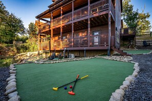A multi-story wooden building with a deck and outdoor seating area. - Heated Indoor Pool | Mtn Views | Fenced Yard | 12 (Sevierville)