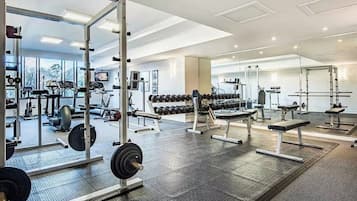 Uma academia com equipamentos de musculação, aparelhos de cardio e espelhos nas paredes.