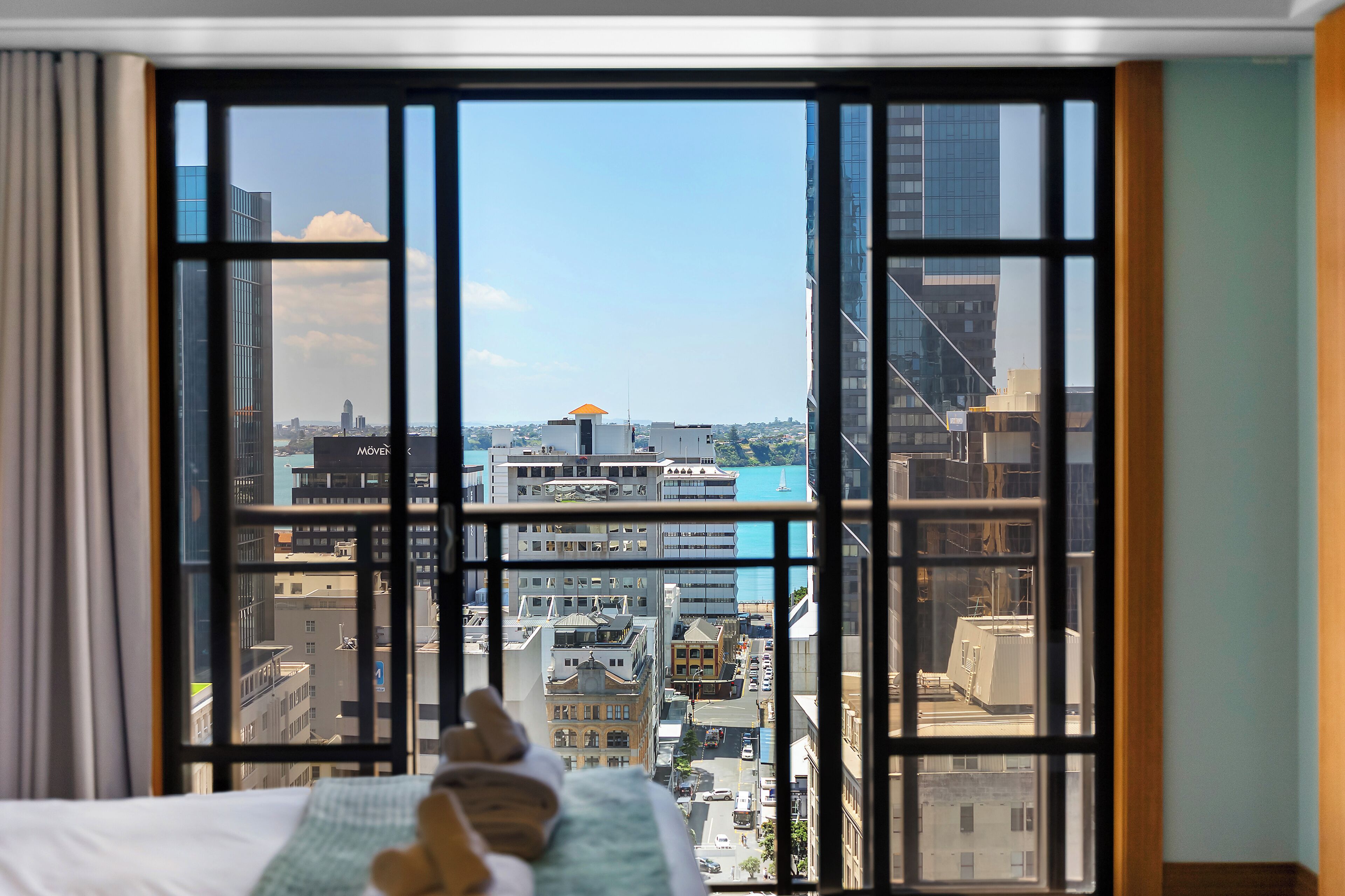 A room with a large window overlooking a cityscape with buildings and a body of water.